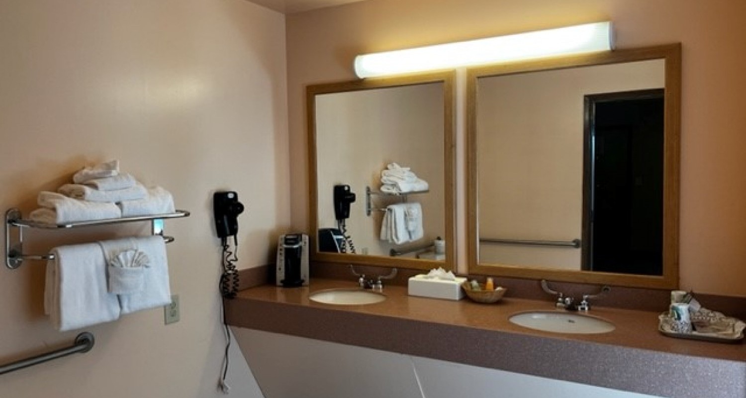 A view of the otherside of the bathroom in the accessible two bedroom suite. There are two sinks at wheelchair height, and additional railings on the wall.