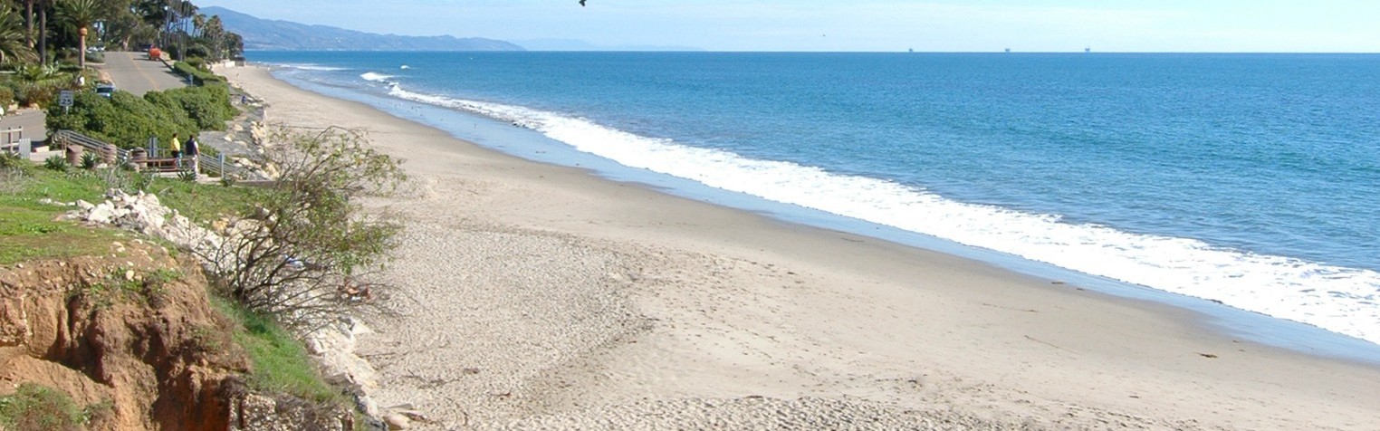 A side-view of the nearby Butterfly Beach with a parasail in the distance.