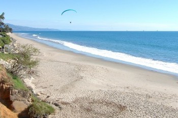A side-view of the nearby Butterfly Beach with a parasail in the distance.
